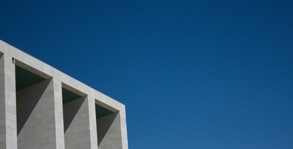 A row of white concrete frames against a deep blue sky