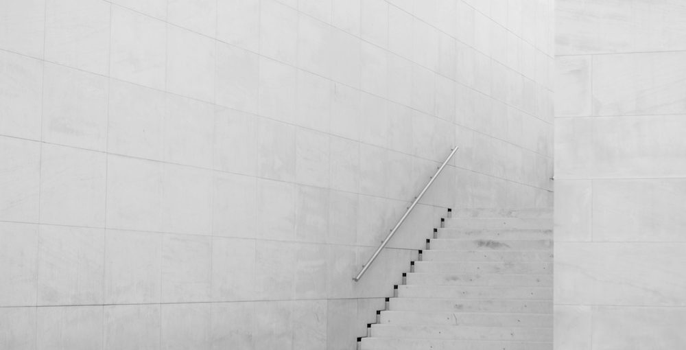 A single slim staircase crossing a pale concrete wall