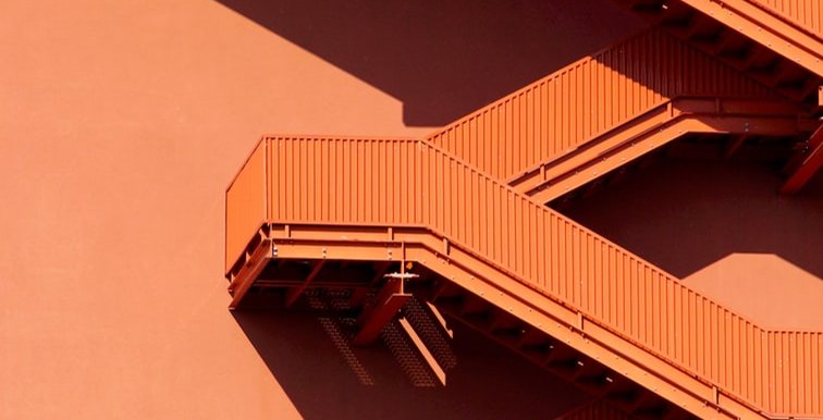 Bright orange staircases climbing a building wall
